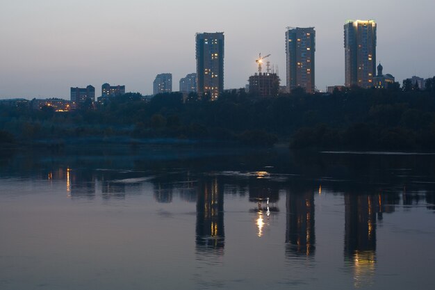 Drie gebouwen in de avond worden weerspiegeld in het water