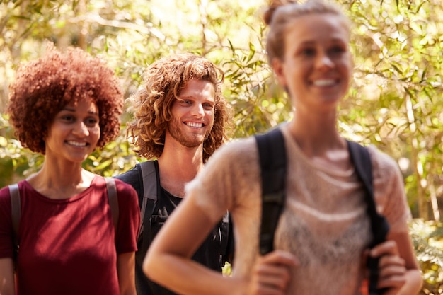 Drie gelukkige millennial-vrienden die rugzakken dragen tijdens een wandeling in een bos van dichtbij