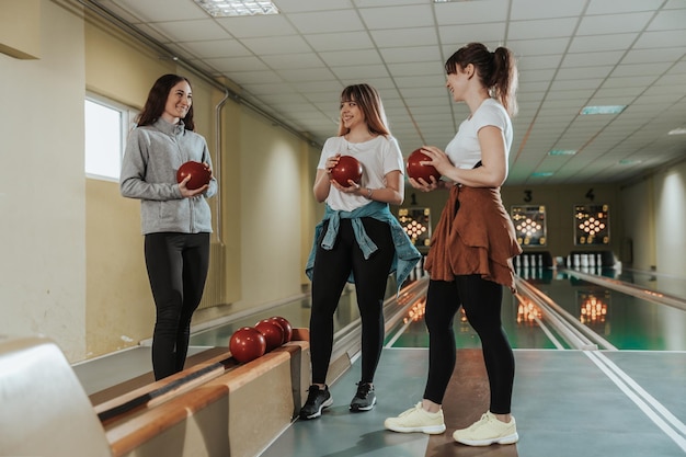 Drie gelukkige vriendinnen hebben plezier in de bowlingclub.
