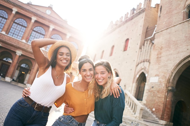 Foto drie gelukkige vrouwelijke vrienden die plezier hebben buiten in de zomervakantie in het stadsportret van een glimlachende vrouw
