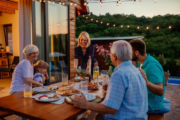 Foto drie generaties familiefamilie tijdens diner samen vakantie vieren in de achtertuin