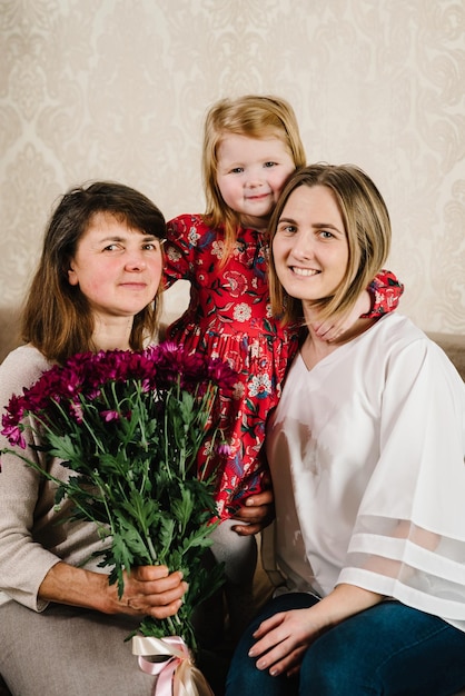 Drie generaties vrouwen Head shot portret kleindochter moeder grootmoeder zittend op de bank thuis kijken naar camera glimlachen tijd samen doorbrengen Internationale Vrouwendag Happy Mother's Day