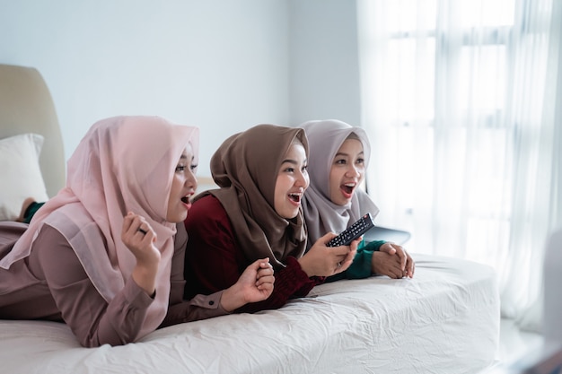 Drie gesluierde vrouw liggend op het bed genieten van het kijken naar de tv