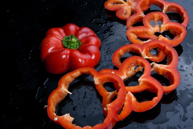 Drie gesneden oranje en rode paprika. Zwarte achtergrond.