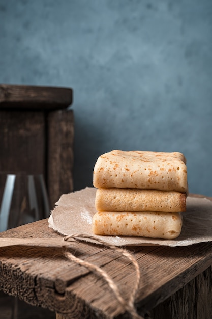 Drie gevouwen pannenkoeken op een papieren bord. Zijaanzicht, met ruimte om te kopiëren.