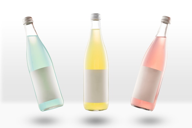 Drie glazen flessen limonade en koolzuurhoudende dranken, met lege mockup labels. geel, roze en lichtgroen. Leeg voor ontwerpers