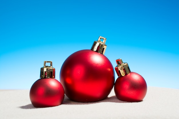 Drie glazen kerstballen op het strand