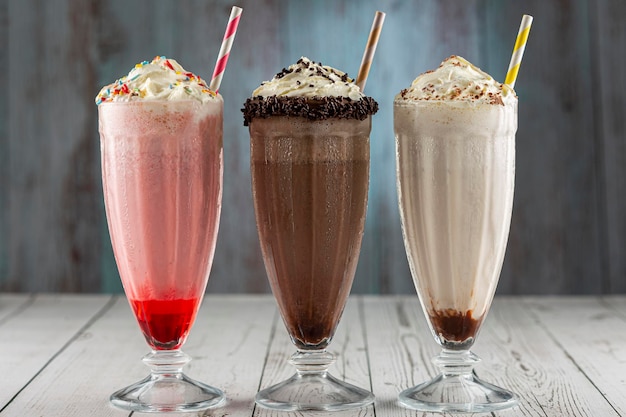 Drie glazen milkshake met diverse smaken. Chocolade, vanille en aardbeienmilkshake.