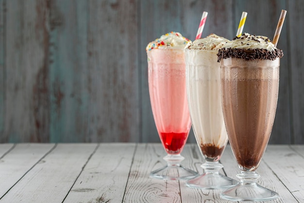 Drie glazen milkshake met diverse smaken. Chocolade, vanille en aardbeienmilkshake.