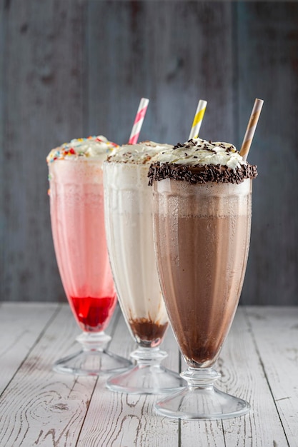 Foto drie glazen milkshake met diverse smaken. chocolade, vanille en aardbeienmilkshake.