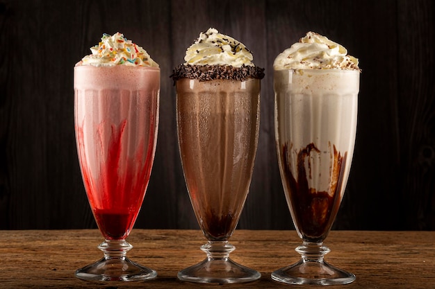 Drie glazen milkshake met diverse smaken. Chocolade, vanille en aardbeienmilkshake.