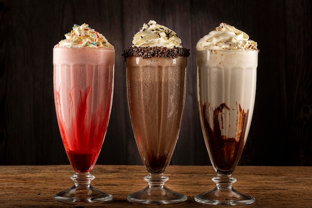 Drie glazen milkshake met diverse smaken. chocolade, vanille en aardbeienmilkshake.