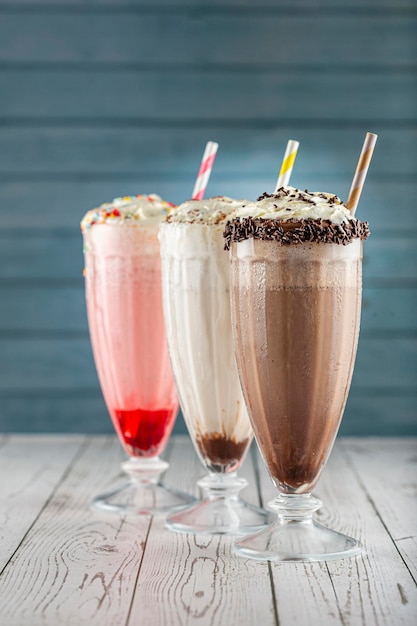 Foto drie glazen milkshake met diverse smaken. chocolade, vanille en aardbeienmilkshake.