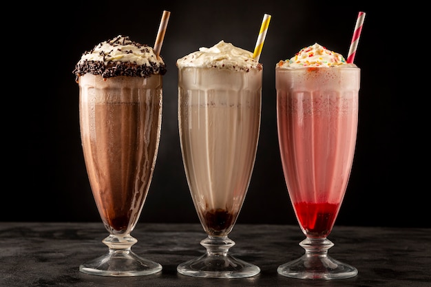 Drie glazen milkshake met diverse smaken. Chocolade, vanille en aardbeienmilkshake.