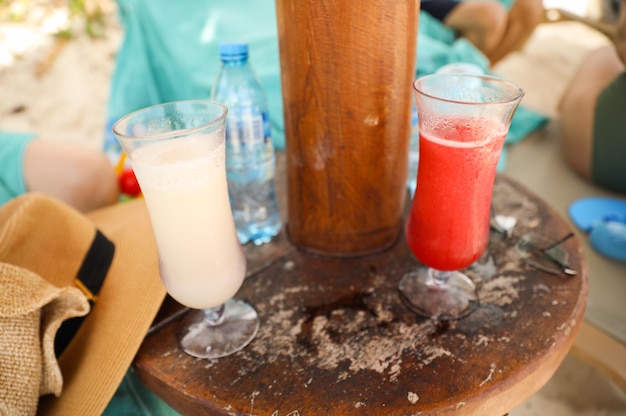 Drie glazen verschillende drankjes op een tafel met een fles water op tafel.