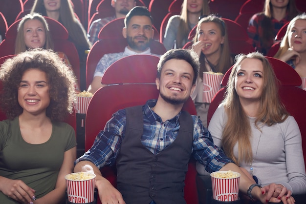 Drie glimlachende beste vrienden die vrije tijd doorbrengen bij bioskoop.