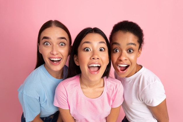 Drie grappige meisjes kijken naar de camera op een roze achtergrond HighAngle
