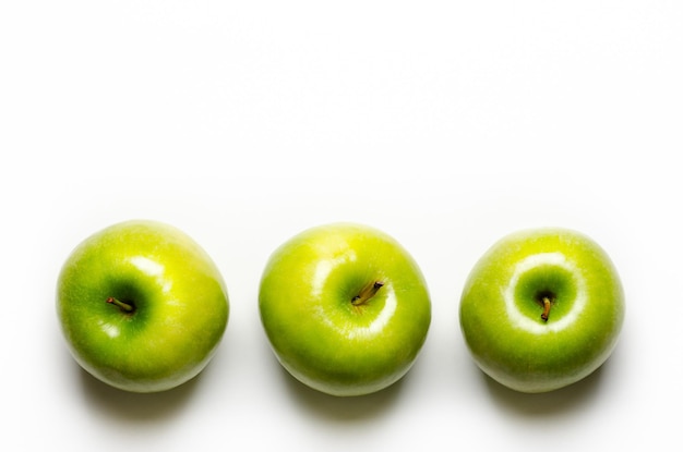 Drie groene appels op witte achtergrond met kopie ruimte.