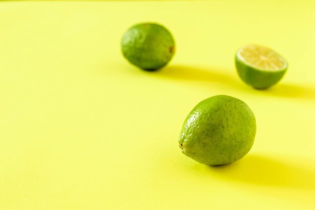 Drie groene limoenen op een geelgroene achtergrond. Citrusvruchten voor het maken van een drankje.