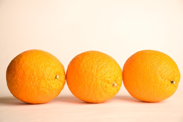 Drie grote identieke sinaasappelen liggen op een rij op een witte achtergrond