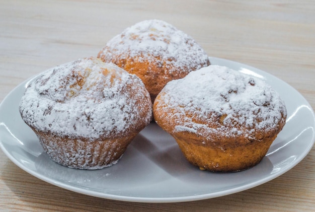 Drie grote shortbread cupcakes met zoete suikerpoeder op een witte plaat