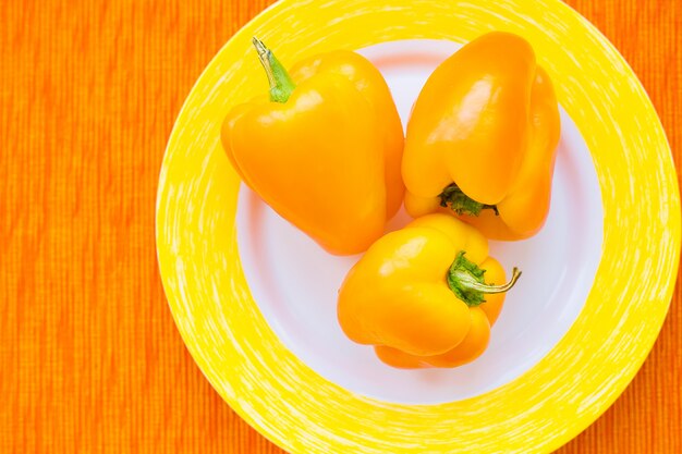 Foto drie heldere gele peper op een plaat sluit omhoog