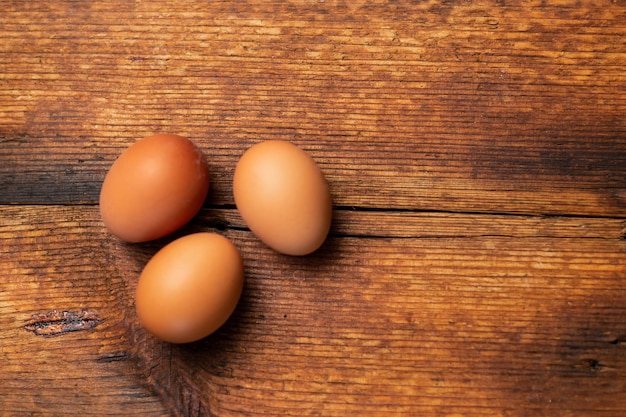 Drie hele kippeneieren op een houten oppervlak plaats voor tekst