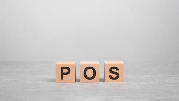 Drie houten blokken met de letters POS op de heldere grijze tafel bedrijfsconcept POS kort voor Point Of Service