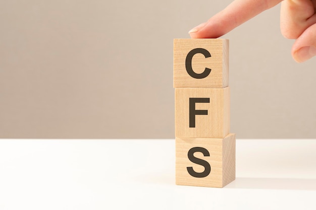 Drie houten kubussen met de letters cfs op het heldere oppervlak van een witte tafel