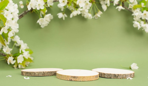 Foto drie houten platforms voor productpresentatie op groene achtergrond met kersenbloesem