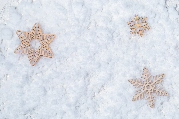 Drie houten sneeuwvlokken op sneeuw