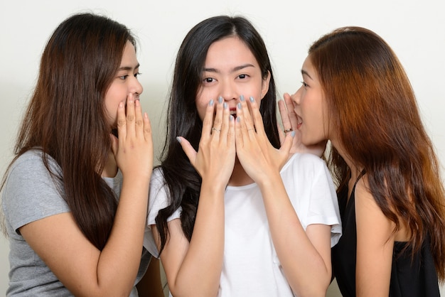 drie jonge Aziatische vrouwen als vrienden samen tegen witte ruimte