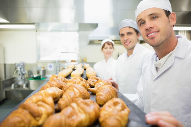 Drie jonge bakkers die in een bakkerij stellen