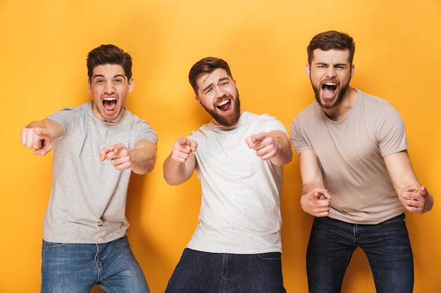 Drie jonge gelukkige mannen wijzen en lachen