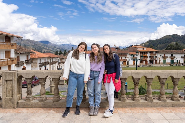 Drie jonge latina-vrouwen poseren op een brug van een traditionele Andes-stad