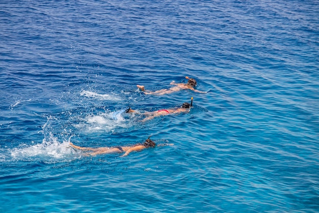 Drie jonge meisjes snorkelen in blauwe wateren boven koraalrif op de rode zee in Sharm El Sheikh, Egypte Mensen en lifestyle concept Bovenaanzicht