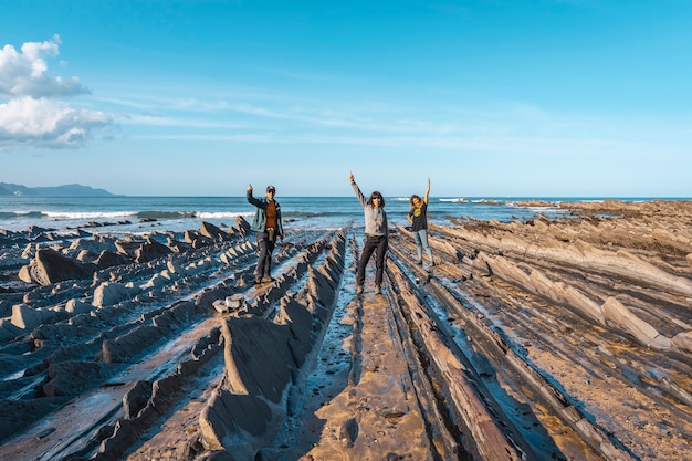 Drie jonge mensen aan de kust van sakoneta groeten