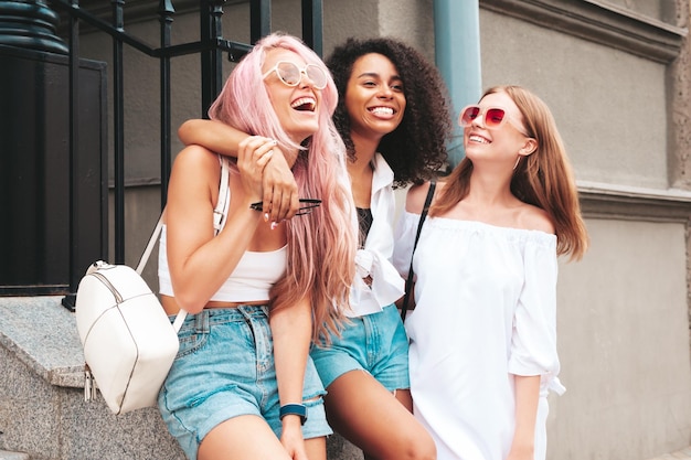 Drie jonge mooie lachende vrouw in trendy zomerkleren Sexy zorgeloze multiraciale vrouwen poseren op de straat achtergrond Positieve modellen plezier in zonnebril vrolijk en gelukkig