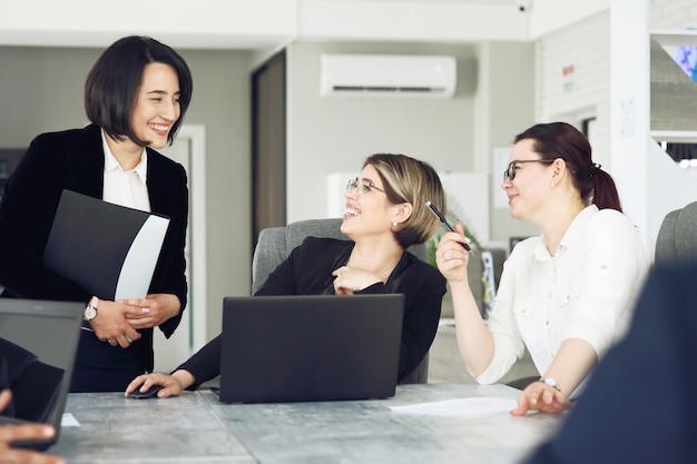 Drie jonge succesvolle zakenvrouwen op kantoor werken samen graag aan een project