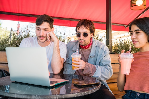 Drie jonge vrienden die laptop met behulp van bij koffiewinkel.