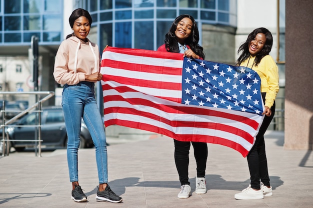 Drie jonge vrienden van de universiteits Afrikaanse Amerikaanse dames met vlag van de V.S.