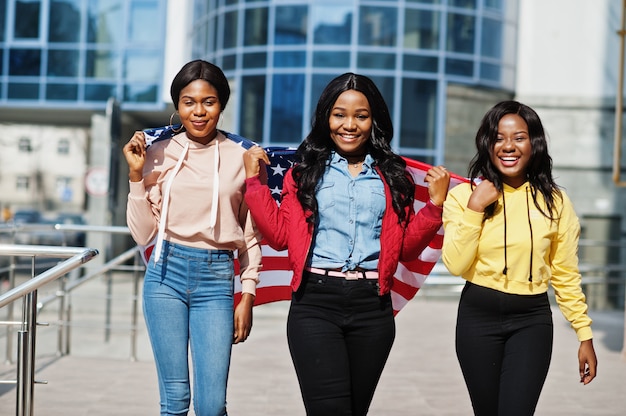 Drie jonge vrienden van de universiteits Afro-Amerikaanse vrouw met vlag van de VS.