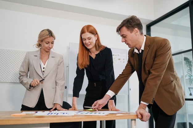 Drie jonge zakelijke professionals die samen staan en discussiëren over een bedrijfsrapport