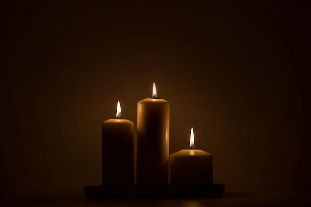 Drie kaarsen die fel branden in het donker
