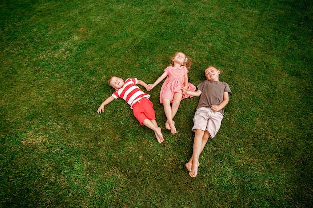 Drie kinderen die op het gras liggen en pret hebben