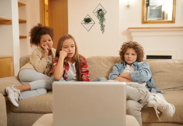 Drie kinderen kijken naar iets op een laptop