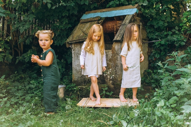 drie kinderen spelen dichtbij de put op een achtergrond van gras en bomen