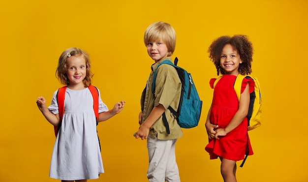 Drie kinderen van studenten verschillende etnische groep met schoolrugzakken