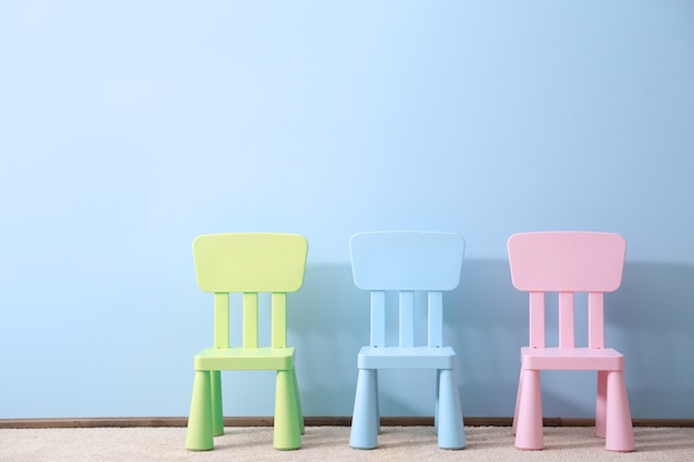 Drie kinderstoelen op blauwe muur