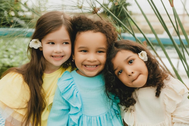 Drie kleine meisjes in de tuin, kinderen van verschillende nationaliteiten, twee donkere baby's en een blank meisje